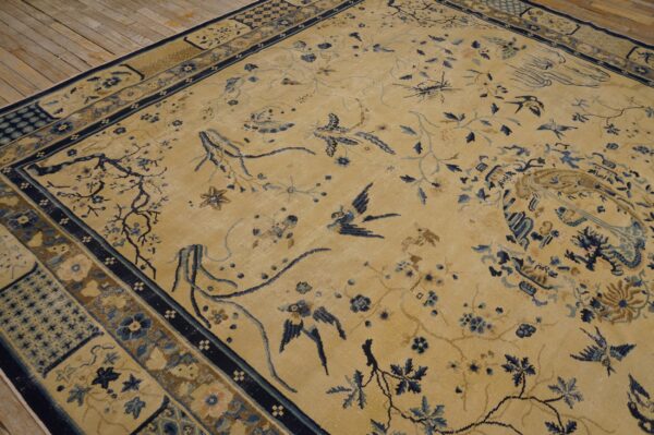 Gold and blue rug featuring birds and vines rests on natural wood plank flooring.