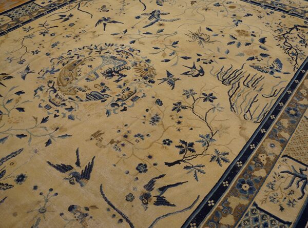 A low-pile rug with a beige field features an intricate pattern of blue birds, vines, and floral motifs.