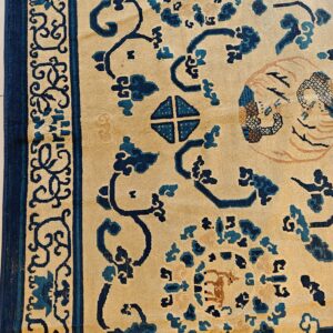 Beige rug with dark blue stylized floral and geometric patterns, showing a defined patterned border.