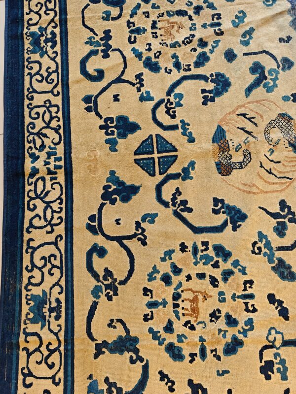 Beige rug with dark blue stylized floral and geometric patterns, showing a defined patterned border.