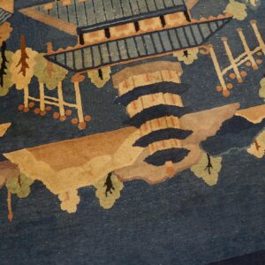 Blue pictorial rug detail featuring tan pagodas, stylized green trees, and brown landscape elements.
