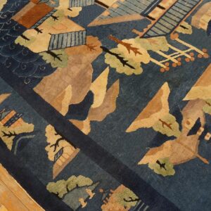 Close-up of a blue rug featuring abstract scenic patterns in tan, rust, and sage green on a light wood floor.