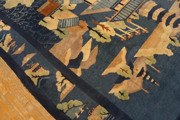 Close-up of a blue rug featuring abstract scenic patterns in tan, rust, and sage green on a light wood floor.