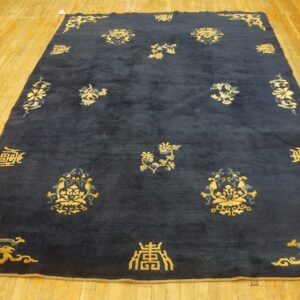 Dark blue rug featuring ornate gold and gray traditional motifs and symbols on a rustic wood floor.