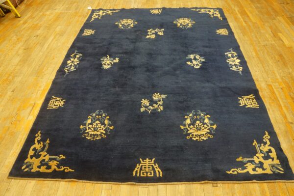 Dark blue rug featuring ornate gold and gray traditional motifs and symbols on a rustic wood floor.