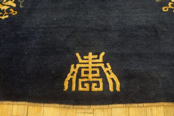 Dark blue high-pile rug featuring a prominent golden patterned symbol on light wooden floors.