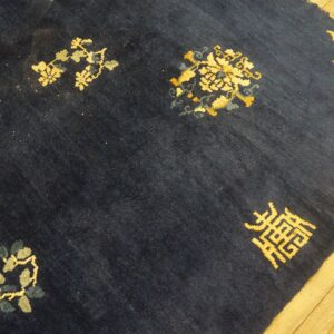 Dark blue high-pile rug with scattered gold and gray motifs lies on a light wood floor.