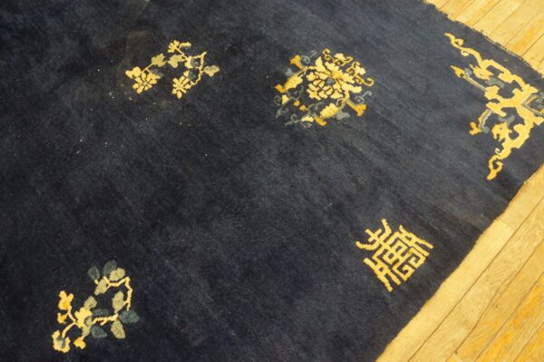 Dark blue high-pile rug with scattered gold and gray motifs lies on a light wood floor.