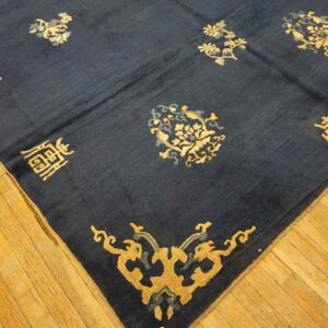 A navy blue rug with gold and gray floral and character motifs rests on worn light wood floorboards.