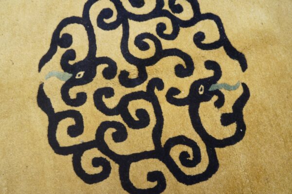 Close-up of yellow high-pile rug with a large, intricate black and teal swirling cloud pattern.