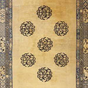 Light tan rug with seven navy scroll medallions and a heavily patterned blue and tan border.