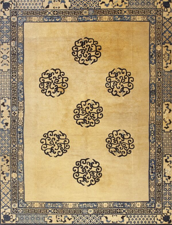 Light tan rug with seven navy scroll medallions and a heavily patterned blue and tan border.