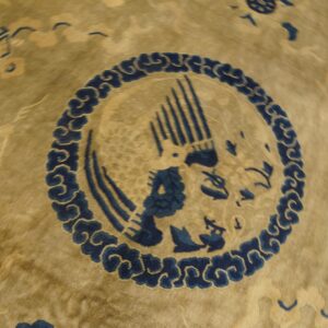 Detail shot of a gold-toned rug featuring a deep indigo circular medallion with a stylized bird.