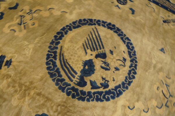 Detail shot of a gold-toned rug featuring a deep indigo circular medallion with a stylized bird.