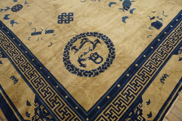 Tan rug with dark blue dragon medallion, scattered symbols, and a detailed geometric key border.