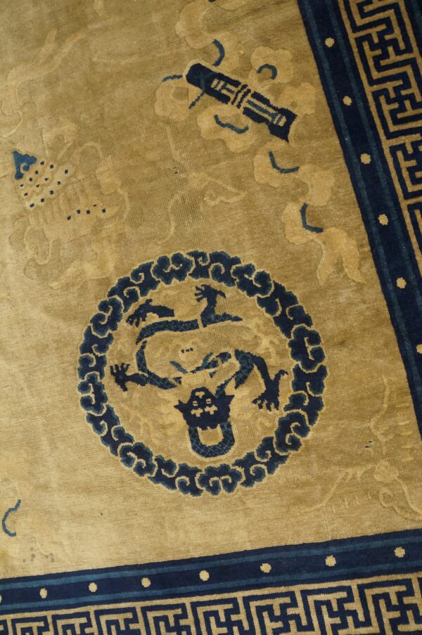 Detailed view of a gold and navy rug featuring a medallion with a mythical beast and geometric borders.