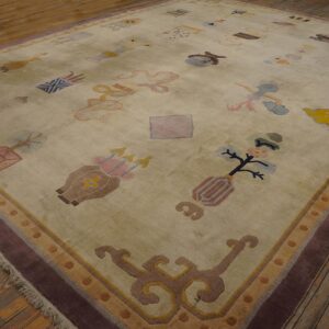Muted beige rug with scattered colorful objects and a wide plum border rests on aged hardwood planks.