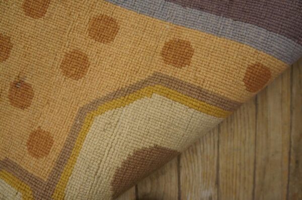 Flatweave rug features tan and brown polka dots with a border of yellow, gray, and purple stripes on wood flooring.