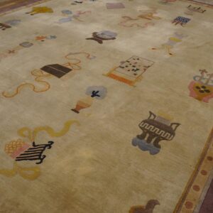 Light green-beige rug with scattered multicolored symbols and a wide maroon border on rustic wood flooring.