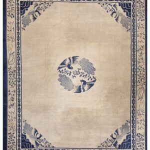 Low pile beige rug featuring a detailed navy blue border and matching bird medallion and corner designs.