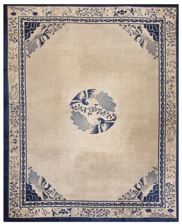 Low pile beige rug featuring a detailed navy blue border and matching bird medallion and corner designs.