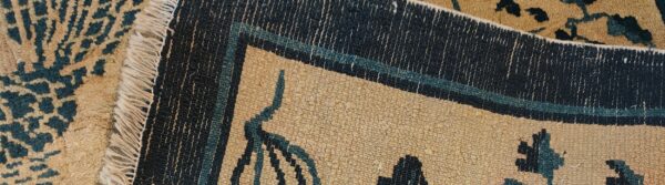 The edges of two rugs overlap, showing contrasting high and low pile patterns in tan and navy.
