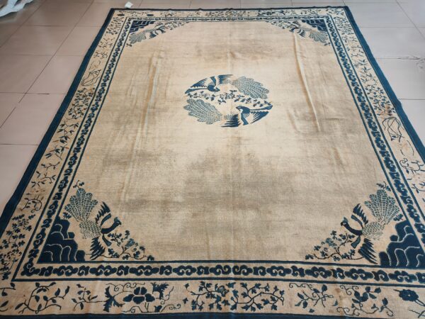 Cream and deep blue rug with a central bird motif and patterned borders, visible on a light tiled floor.