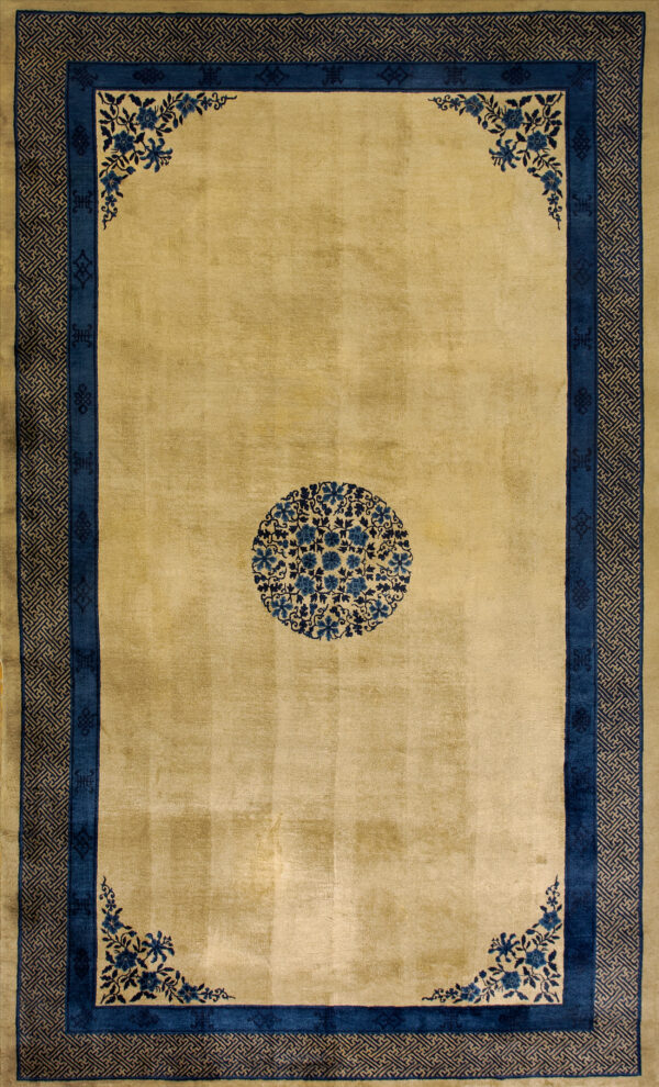 Gold rug featuring a center blue floral medallion, corner floral sprays, and complex geometric borders.