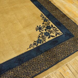 Golden rug featuring deep blue floral corner designs and a geometric fret border on light wood plank flooring.