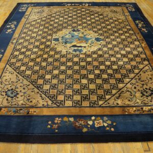 Blue-bordered rug with a detailed gold geometric field and central animal medallion on hardwood flooring.