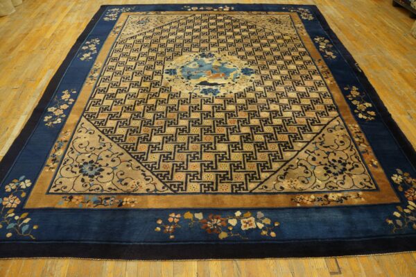 Blue-bordered rug with a detailed gold geometric field and central animal medallion on hardwood flooring.