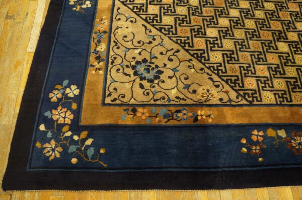Close view of a blue and gold rug showing floral borders and a geometric field design on wood floor.