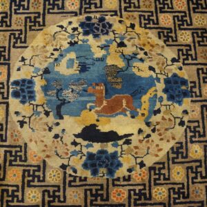 Tan and navy rug featuring a central blue medallion with a rust animal and a dark geometric border.