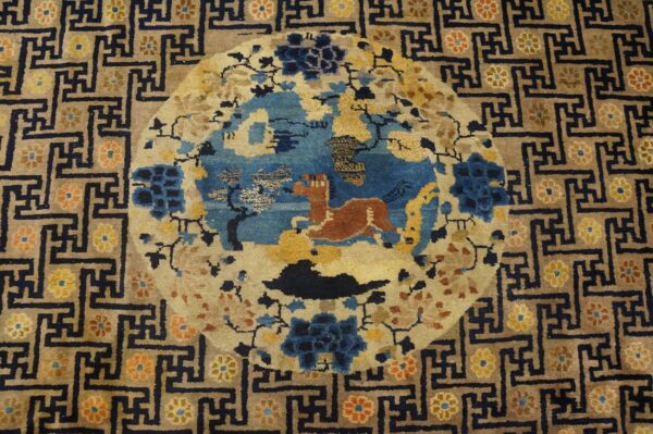 Tan and navy rug featuring a central blue medallion with a rust animal and a dark geometric border.