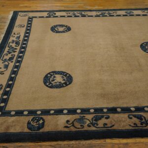 Beige low pile rug with dark blue floral borders and medallions displayed on light wooden flooring.