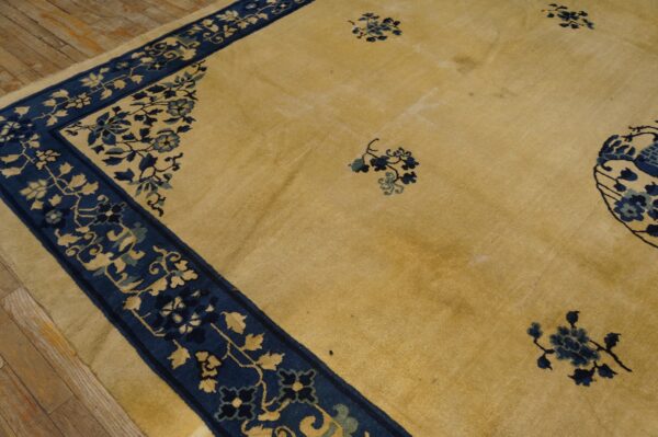 Yellow rug featuring a wide blue border and scattered floral accents on worn wood planks.