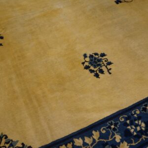 Gold-toned rug with navy blue floral clusters scattered on the field and intricate botanical borders.