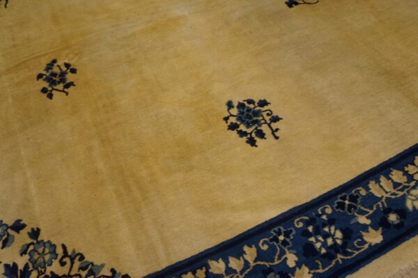Gold-toned rug with navy blue floral clusters scattered on the field and intricate botanical borders.