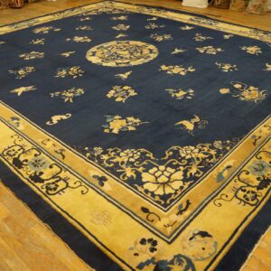 Navy rug with yellow floral pattern, central medallion, and wide decorative border on light wood floors.
