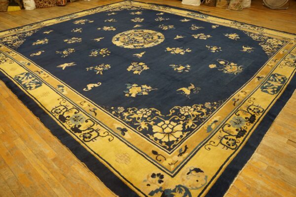 Navy rug with yellow floral pattern, central medallion, and wide decorative border on light wood floors.