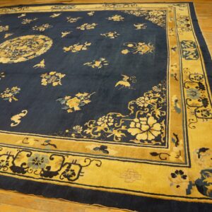 Large navy rug featuring scattered gold and blue floral motifs and a wide gold border on a wood floor.