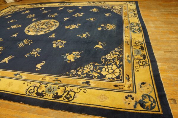 Large navy rug featuring scattered gold and blue floral motifs and a wide gold border on a wood floor.