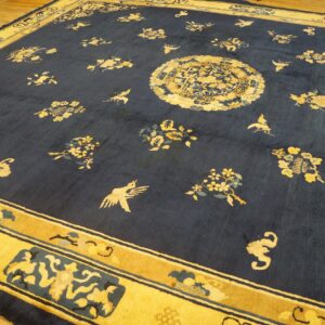 Deep blue rug with gold floral and bird motifs, a central medallion, and wide border on wood flooring.