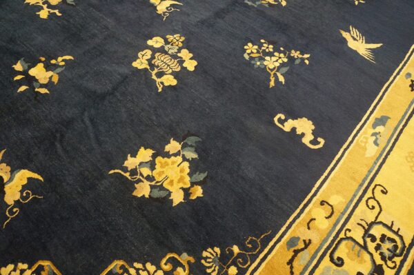 Navy field rug with scattered yellow botanical and bird motifs bordering a golden yellow band.