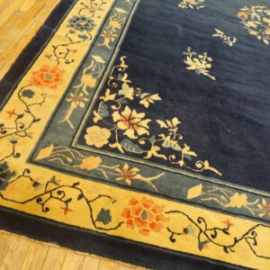 Navy blue rug with a bright yellow floral border rests on light-colored wood plank flooring.