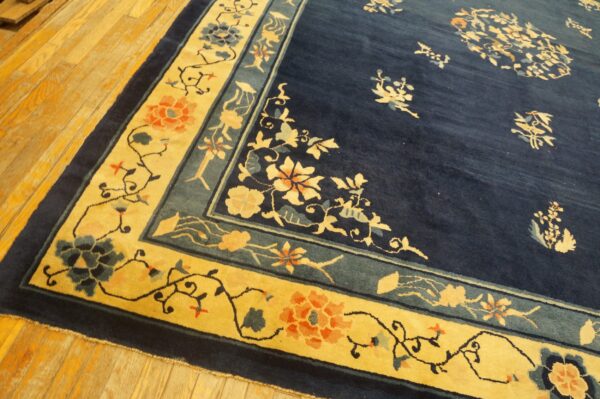 Navy blue rug with a bright yellow floral border rests on light-colored wood plank flooring.