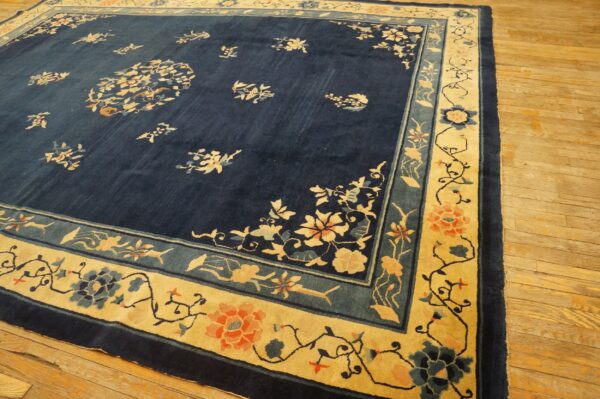 Navy blue floral rug featuring a wide golden yellow border with coral and teal accents on wooden floors.