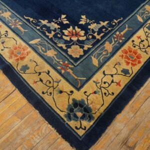 Navy blue rug featuring elaborate gold and teal borders with detailed floral and vine patterns on wood planks.