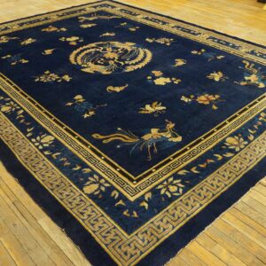 Dark blue rug featuring gold avian and floral patterns and complex geometric borders on wood floors.