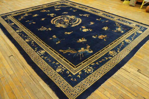 Dark blue rug featuring gold avian and floral patterns and complex geometric borders on wood floors.